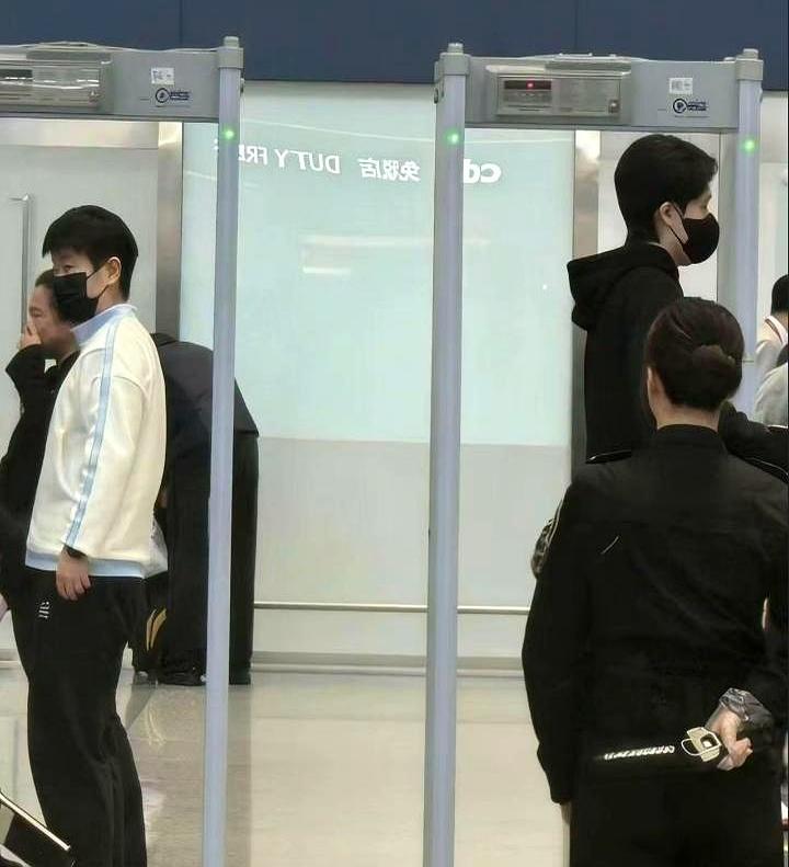 海口机场安检口，左边那个是他，右边那个是她，背靠背，同时通过。
 
周围人挤人，