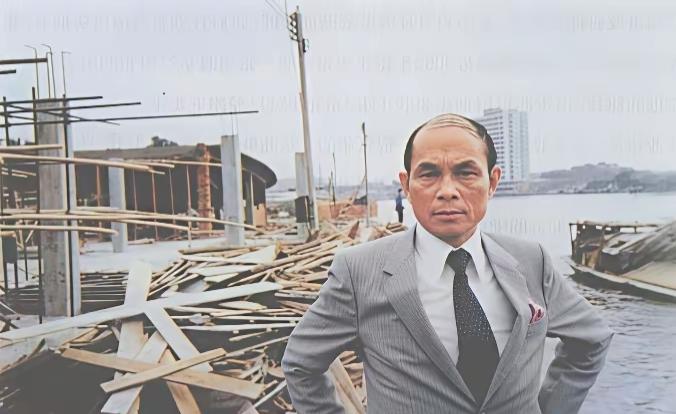 一个穿西装的男子站在废墟前。1980年留影，大家还记得这位爱国人士吗？瞻仰历史人