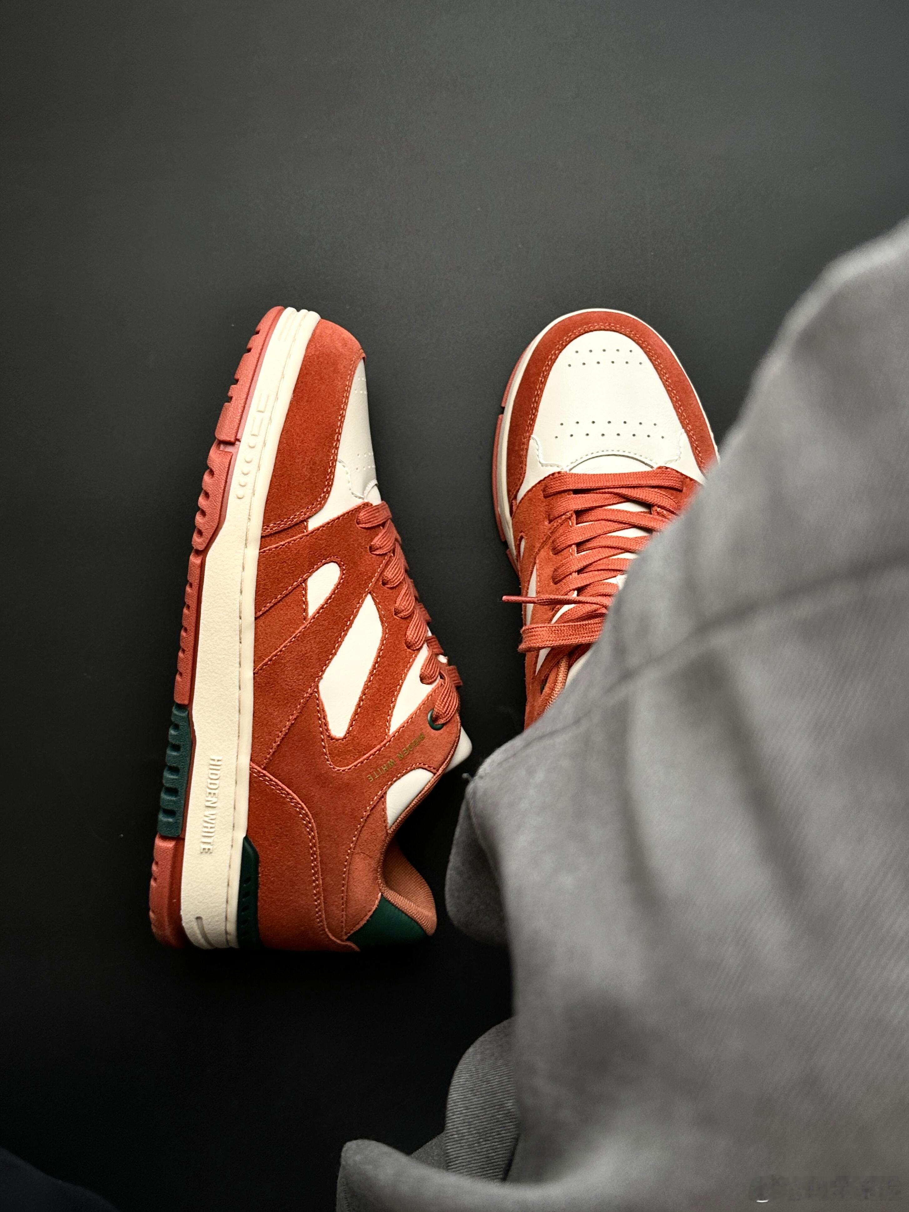 这双运动鞋是一款设计出众的复古风格鞋款，以醒目的橙红色翻毛皮与纯净的白色皮革在鞋