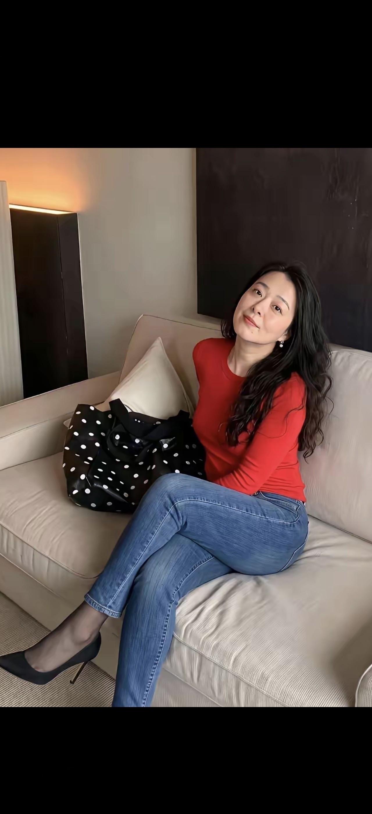这位女士穿着红衫，坐在沙发上。