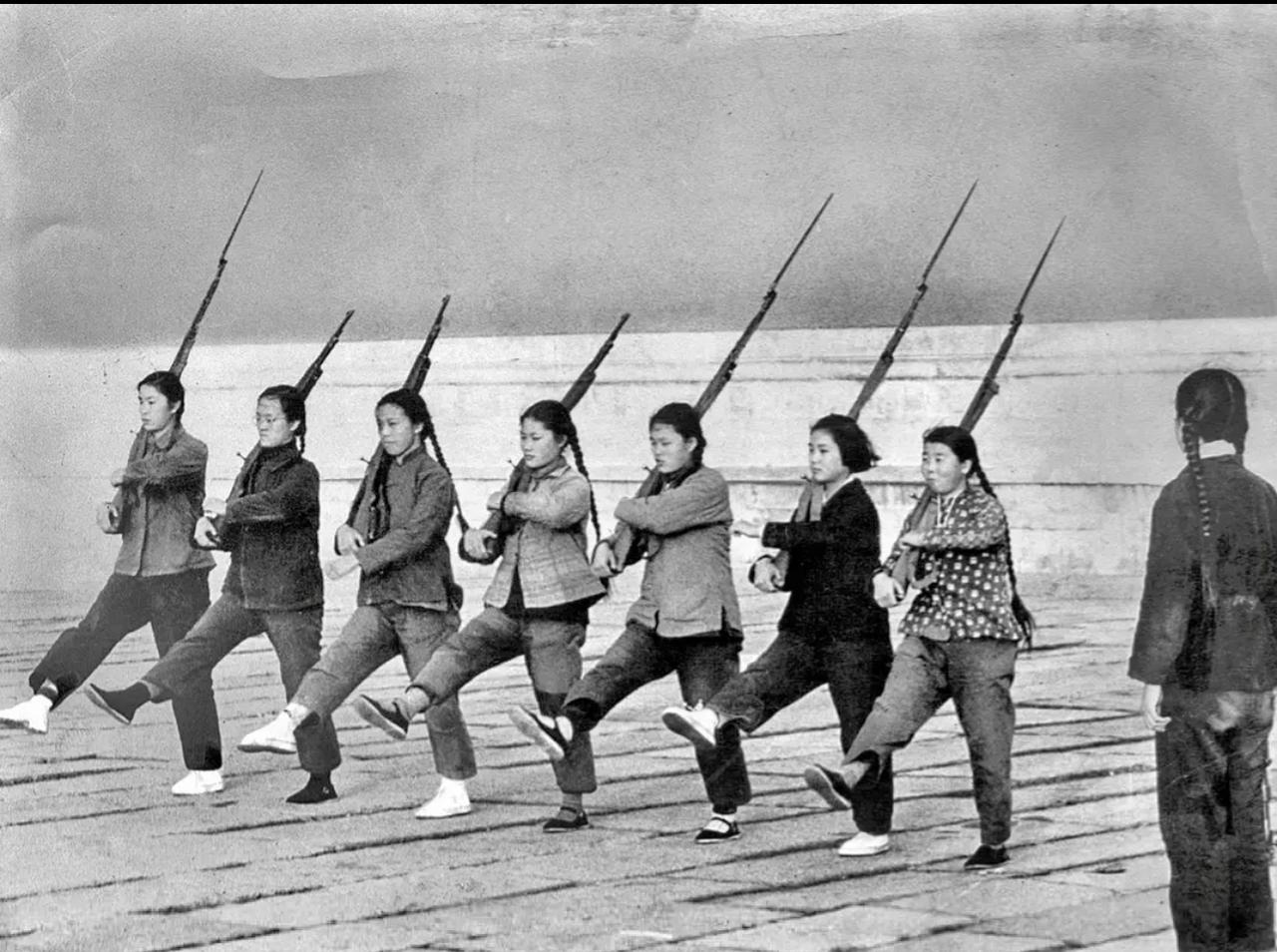 1966年，几位女民兵正在北京故宫旁边训练。

几个姑娘扛着步枪练习踢正步，表情