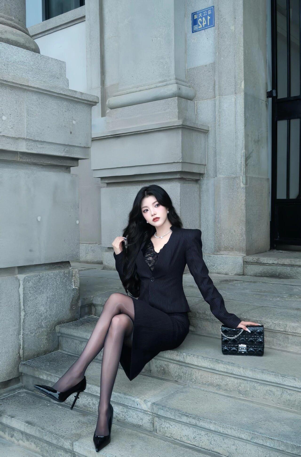 “黑色西装套裙+光泽袜+小高跟”，精致干练，优雅自信
这套黑色套装的上衣是修身款