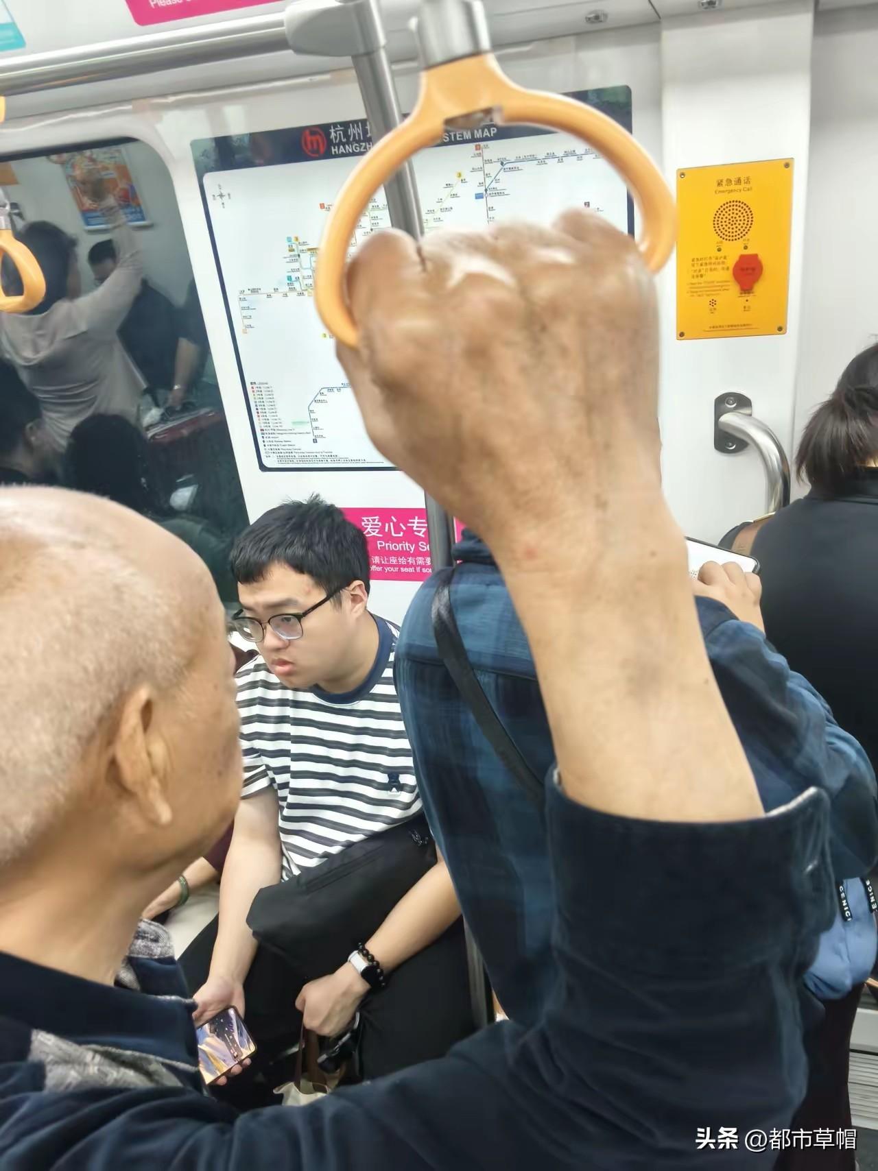 白发苍苍七八十岁的老人站在地铁上，对面“爱心专座”上的年轻人视而不见。他不明白地