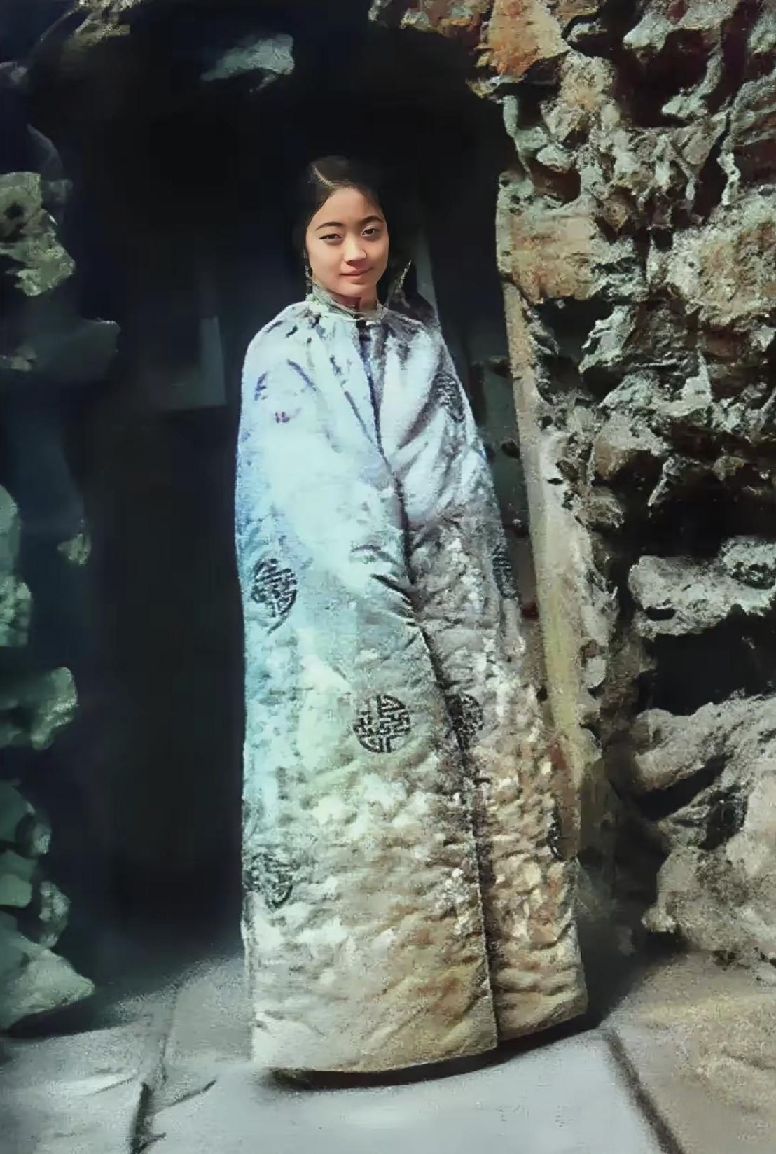 谁能想到，这笑眼盈盈的姑娘竟是末代皇后婉容！
 
裹着绣满寿纹的棉斗篷，蓝料子蹭