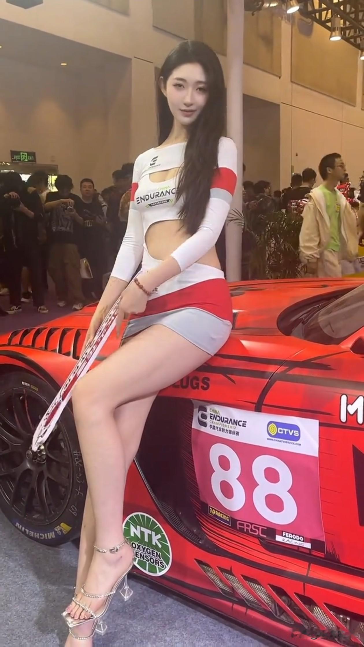 引擎嘶吼震荡展厅，烈焰红赛车携“88”号霸气亮相！模特一袭利落潮装，露腰设计搭配