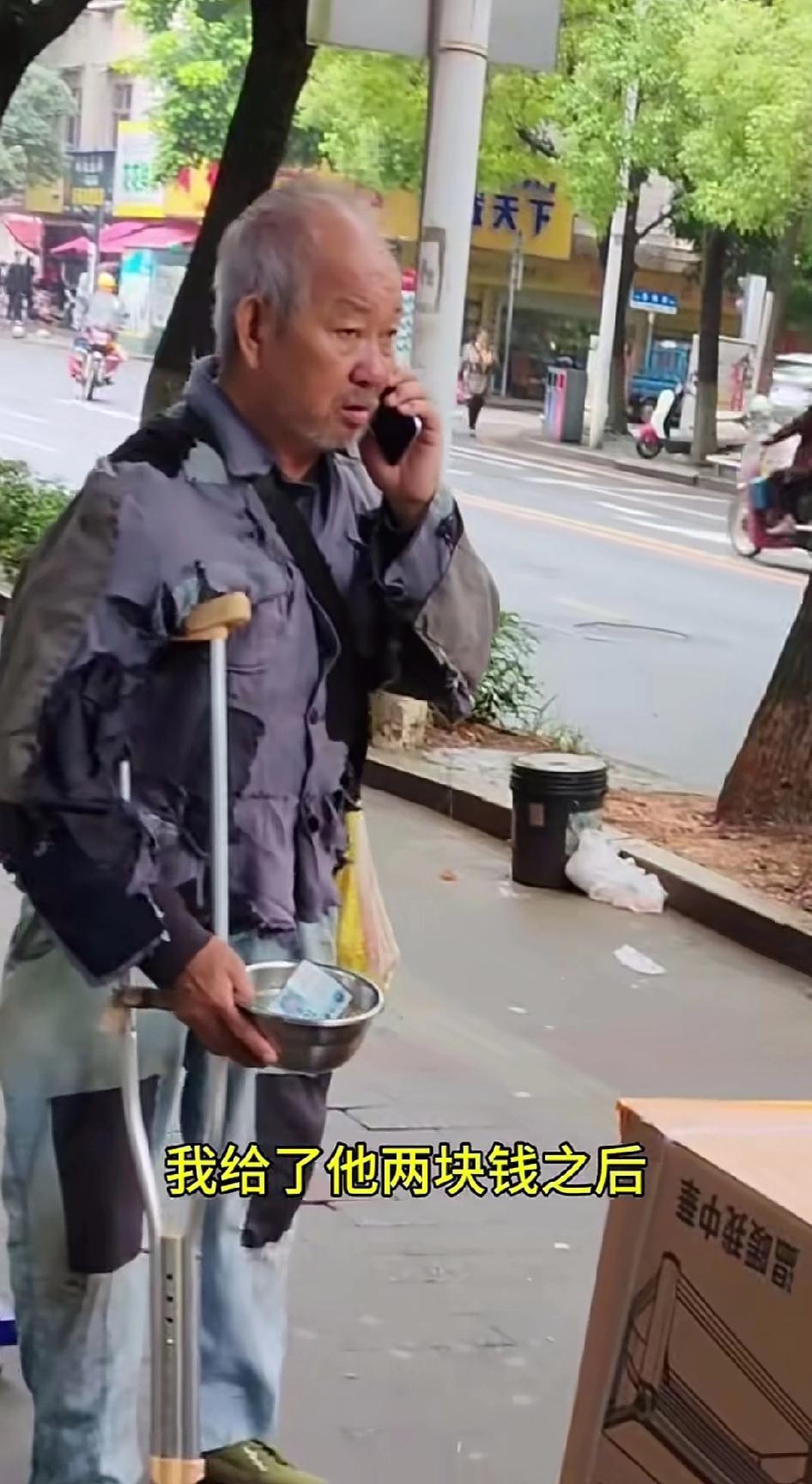 一只手撑着拐杖，另一只手端着个钢盆，身上的衣服满是补丁。这样一个装扮得既像“残疾