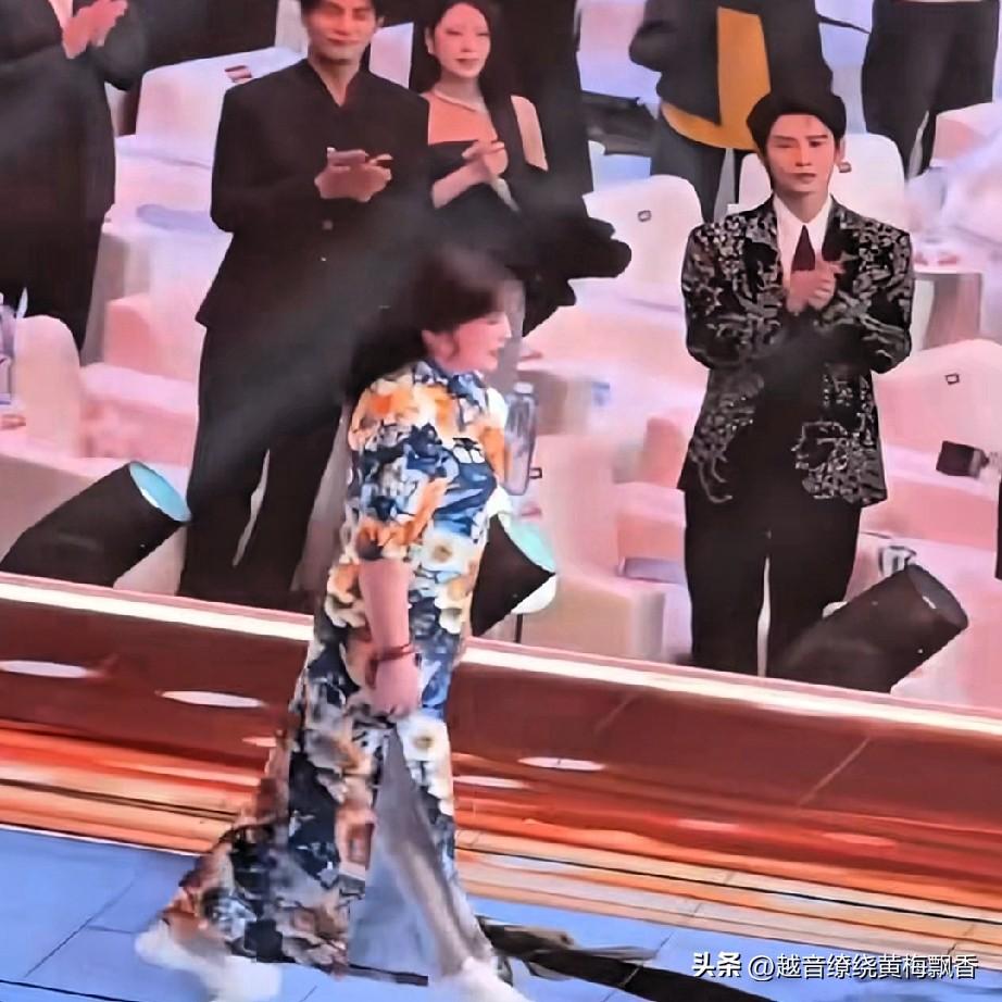 刘晓庆穿着一身花色旗袍上台领奖，所有的人站起来为她鼓掌，从图片上看，75岁的刘晓