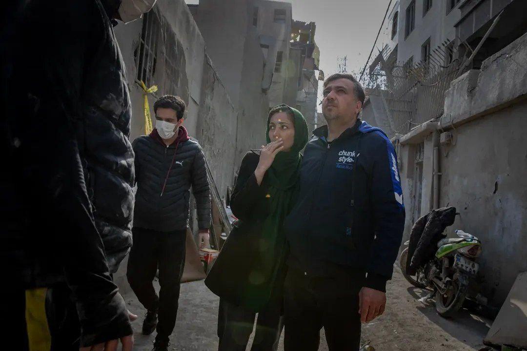 伊朗民众站在被以色列和美国空袭后的废墟中，空袭造成首都德黑兰大范围破坏后的景象。