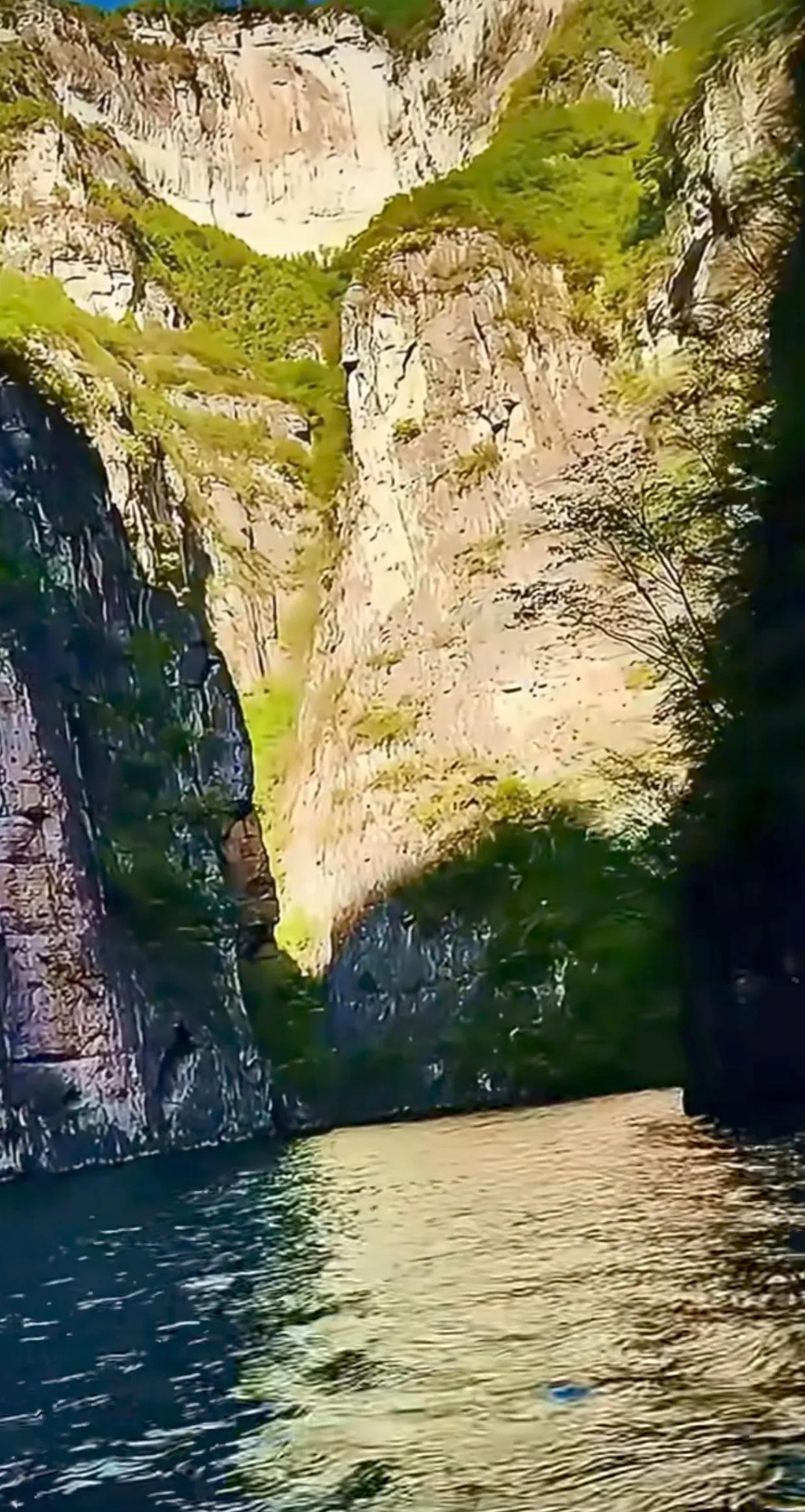 碧波荡漾，峭壁巍峨，阳光洒落的金色诗篇，在嶙峋岩壁与葱郁绿意间流转。光影交错，宛