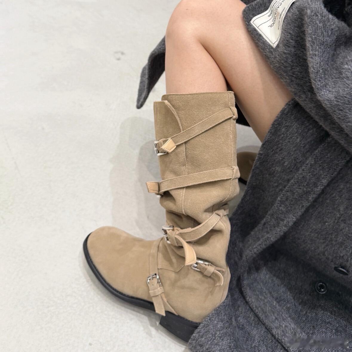 这是一双设计感十足的米色麂皮长筒靴。其最大的亮点在于靴筒侧边的多条平行皮质绑带，