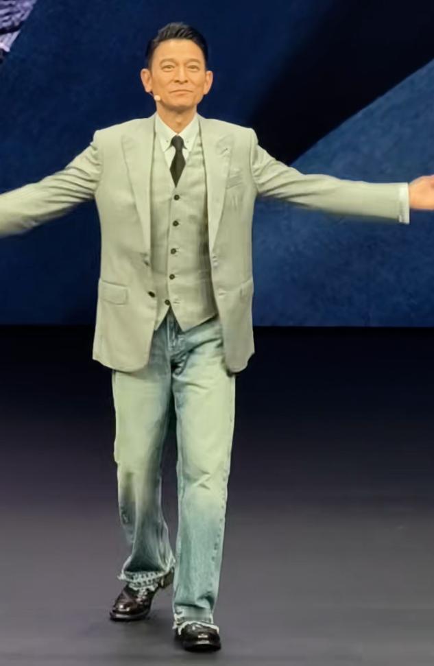看看华仔这一身的穿搭，上身西服下身是牛仔裤，牛仔局的边边还是带碎碎的，脚蹬一双皮