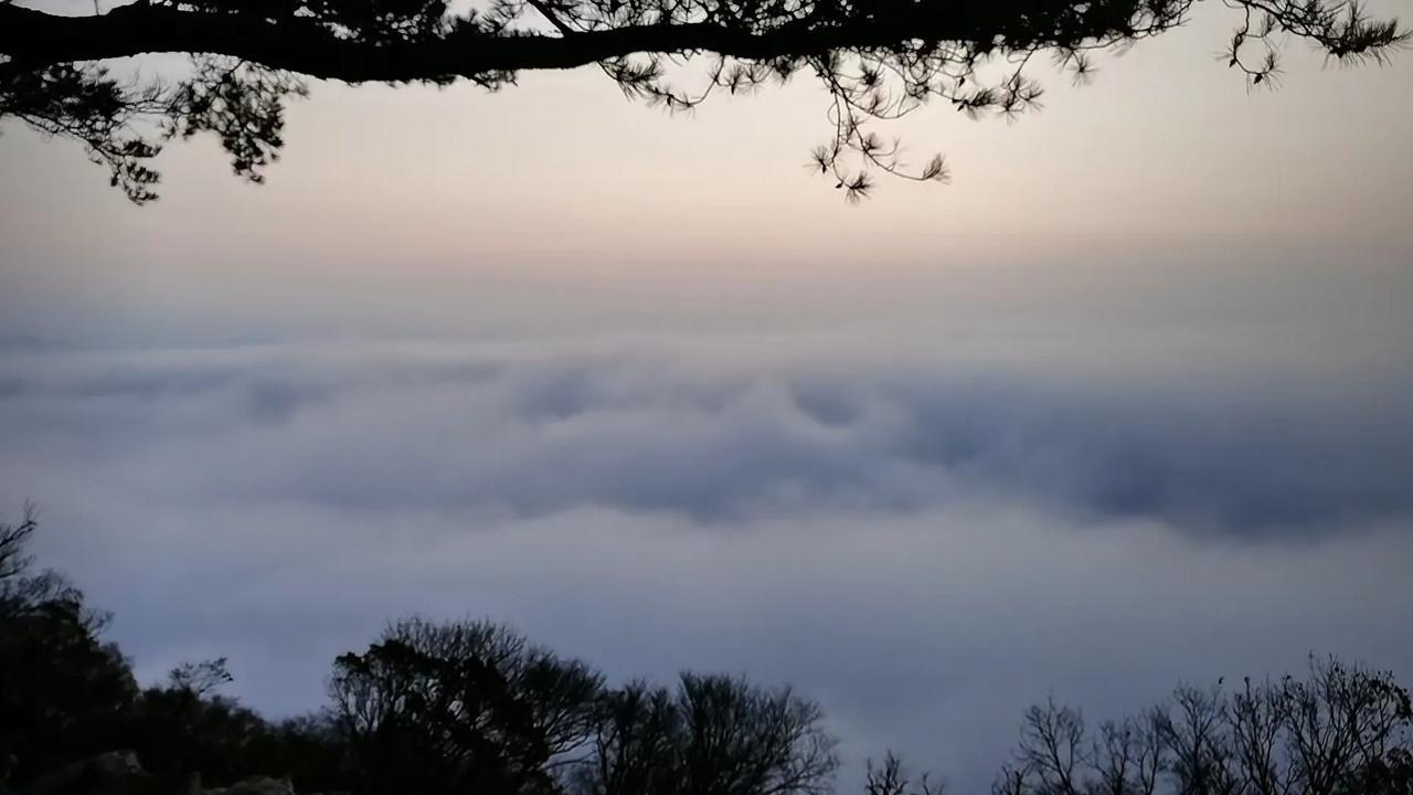 站在山顶，俯瞰那浩瀚无边的云海，如波涛汹涌的白色海洋，翻腾涌动，仿佛置身于仙境之