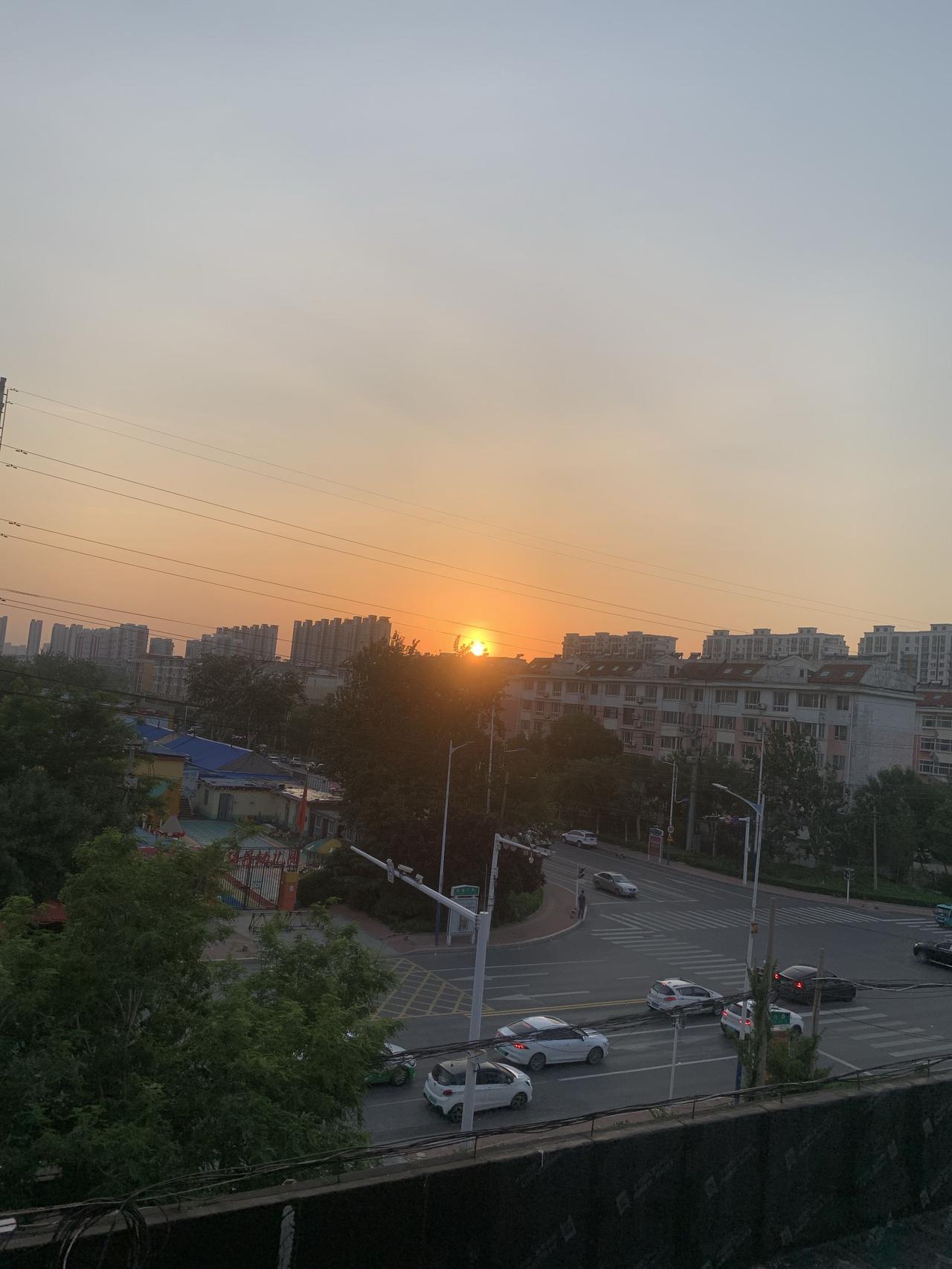 夕阳西下
夕阳西下，小城被染成一片金橘色。路灯和楼房窗内的灯还未点亮，楼顶、马路