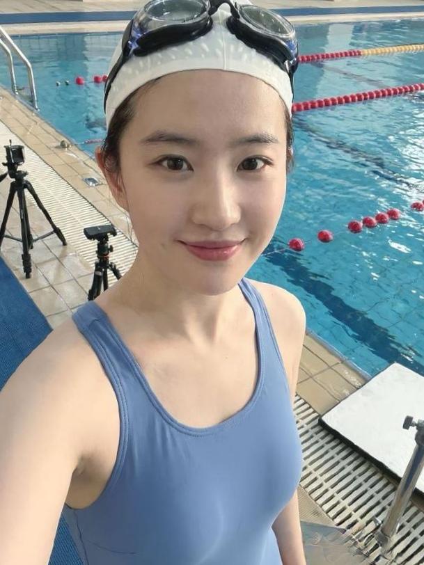 看这张剧照里的刘亦菲，泳池边坐着，湿发贴在颈间，简单的黑色泳装衬得皮肤像月光下的