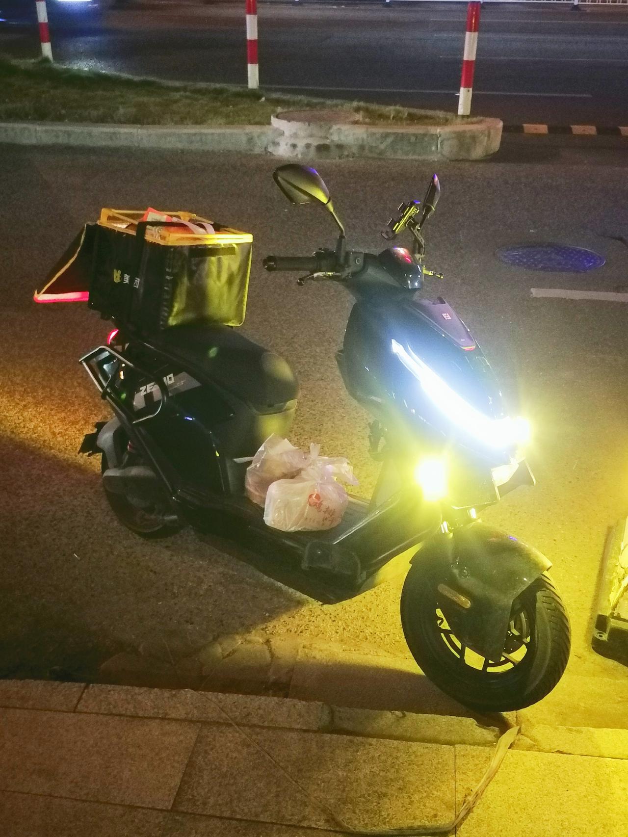 福建泉州，深夜，外卖小哥的电动车和快餐就这样停放在路边，而他提着一份快餐刚跑进3