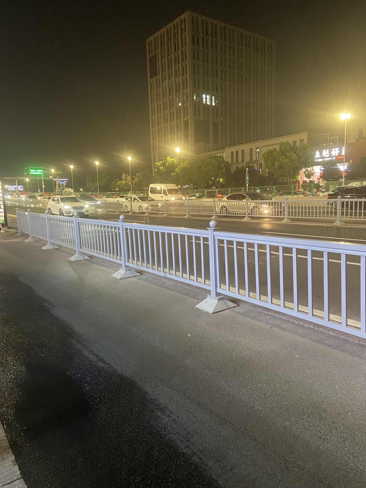 晚上出来溜达，瞧见这马路夜景还挺有意思！白色护栏齐齐整整，马路上车来车往的，路灯