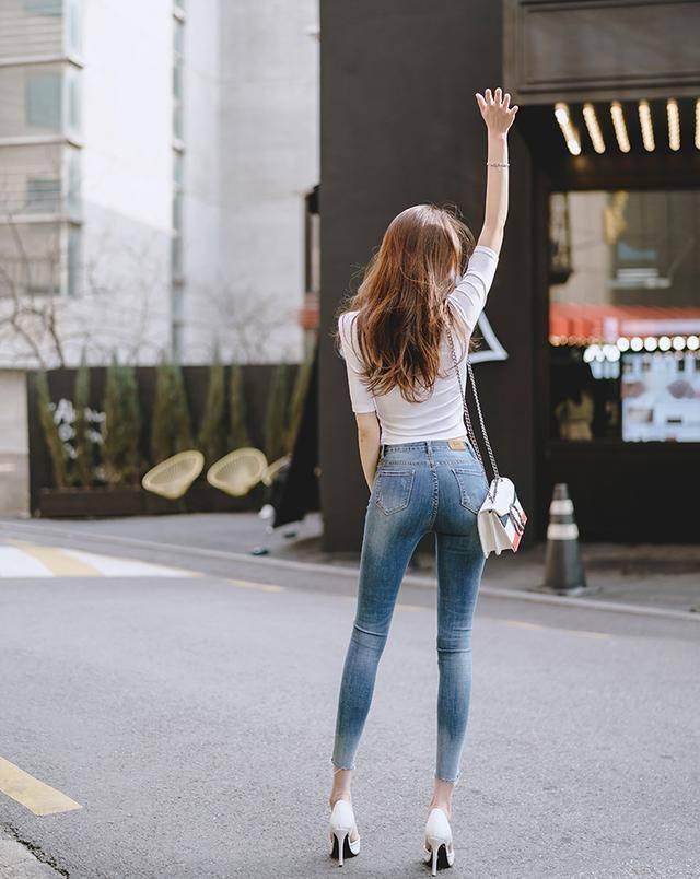 牛仔裤裹着修长的弧线，行走时漾起靛蓝色的涟漪。那不是摇曳的裙裾，而是踏过大地的坦