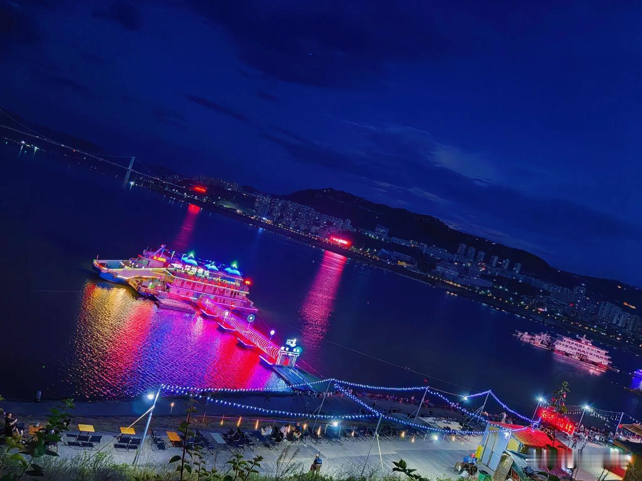 秋夜，万州区北滨路江边夜市摊点，灯火通明人流拥动，凭栏看江景，品茗、赏美食、饮冰