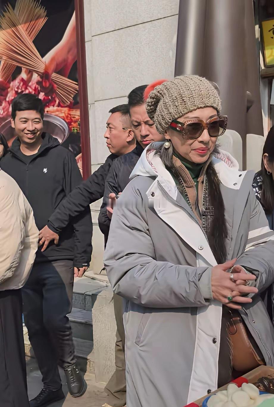 武汉街头偶遇林子祥和叶倩文在买马蹄子吃，64岁的叶倩文头戴帽子，搭配咖色眼镜，穿