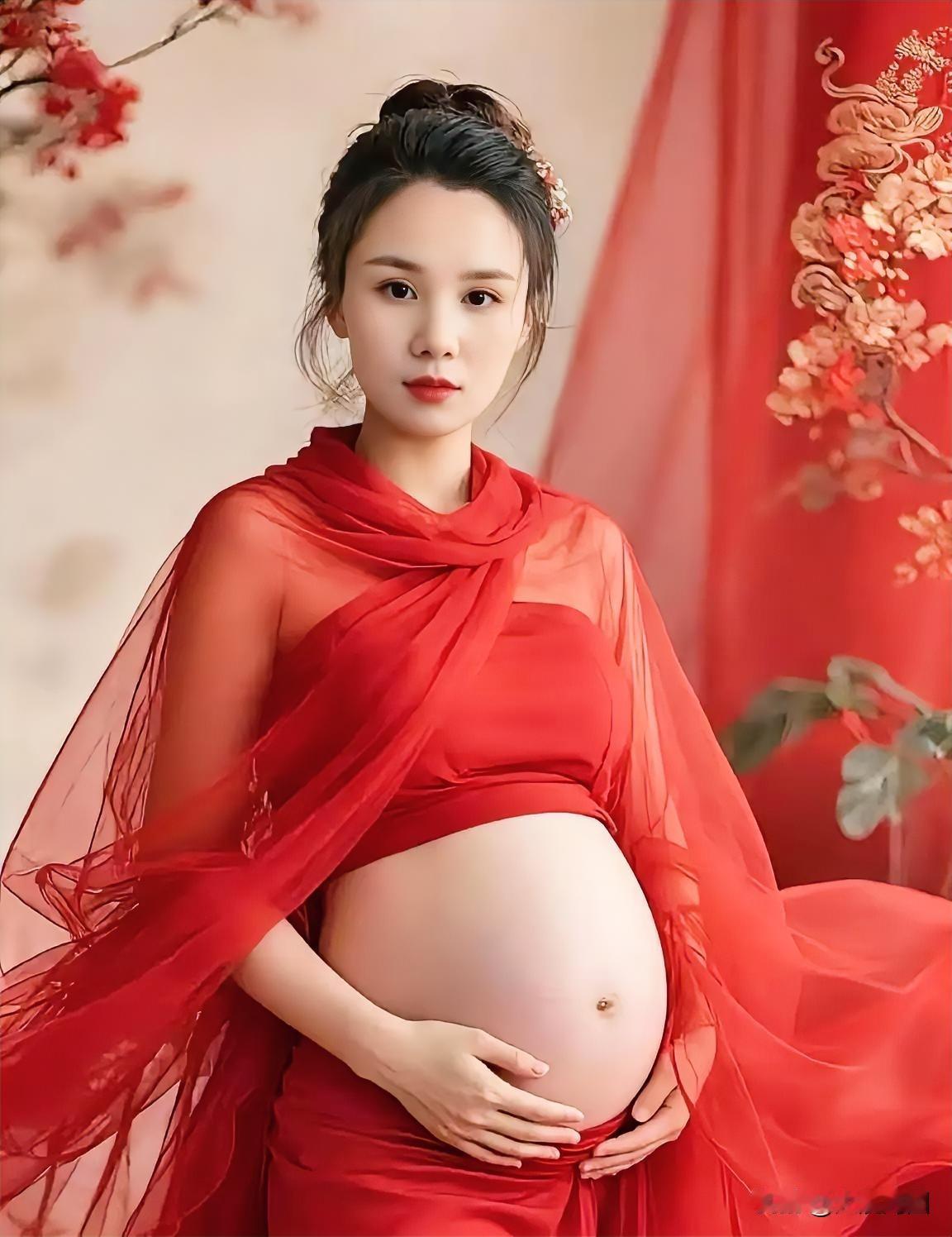 孕妇穿着红色长裙，温柔地抚摸着肚子。