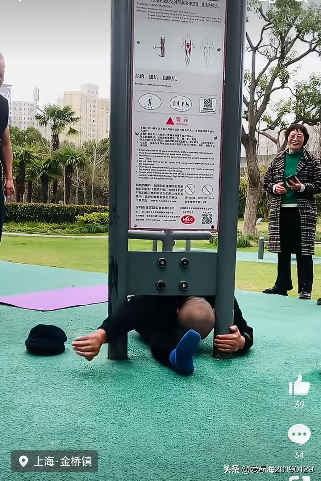 在上海金桥镇的某公园，一位光头大哥，正向旁边的文质彬彬的大姐展示柔韧性的硬核动作