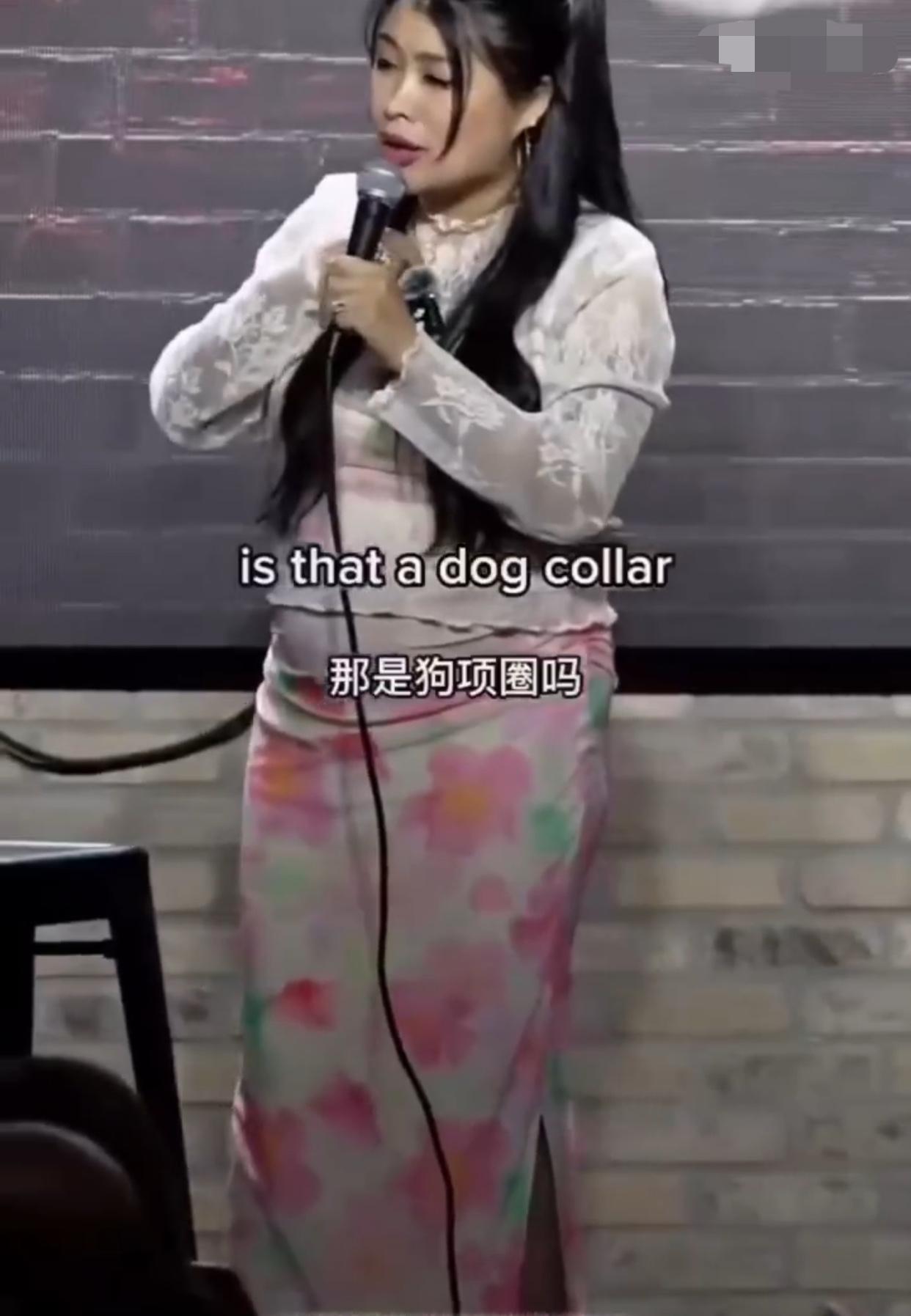 一个国外脱口秀现场：一名白人男子拿着一个类似于狗链的东西拴着一个项圈套在一位越南