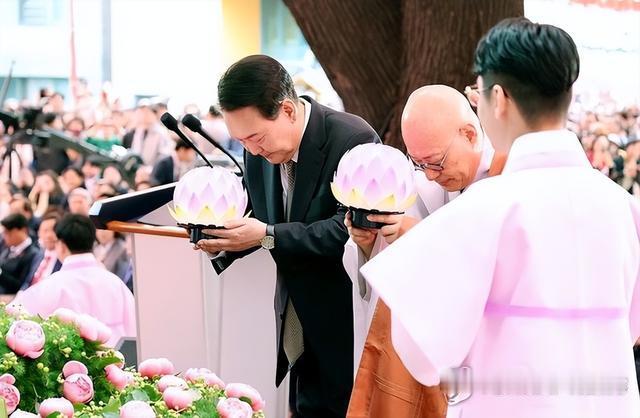 尹锡悦手捧莲花与和尚一起鞠躬，他的样子很虔诚，就是不知他在拜什么？