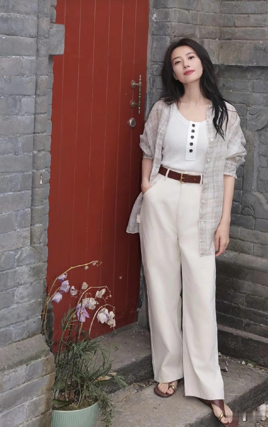 胡同红门前，高圆圆用简约单品搭出慵懒松弛感。内搭选了带纽扣设计的白色背心，外披格