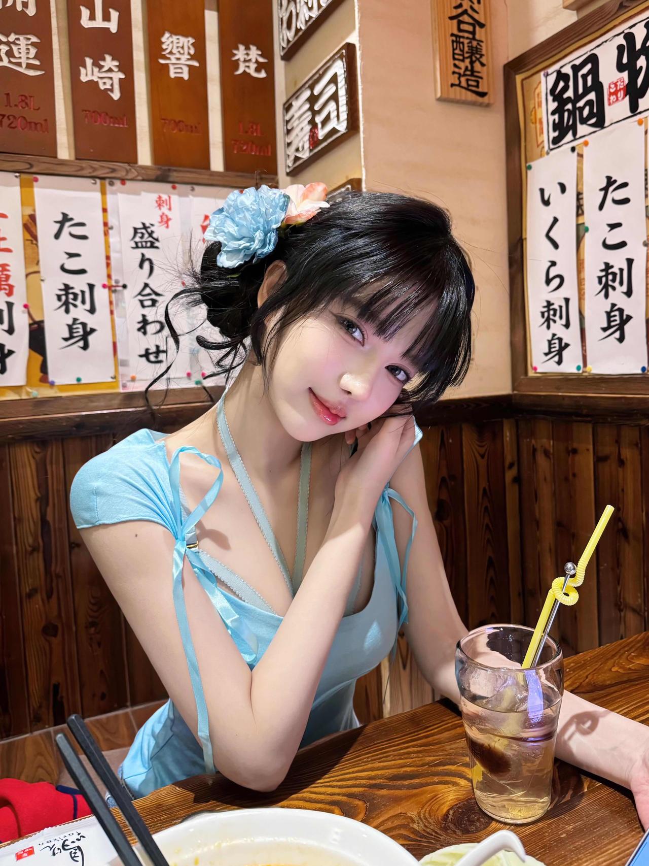 在日式居酒屋暖黄的灯光里，邂逅一位身着浅蓝色纱裙的姑娘——发丝挽着淡蓝花朵，睫毛