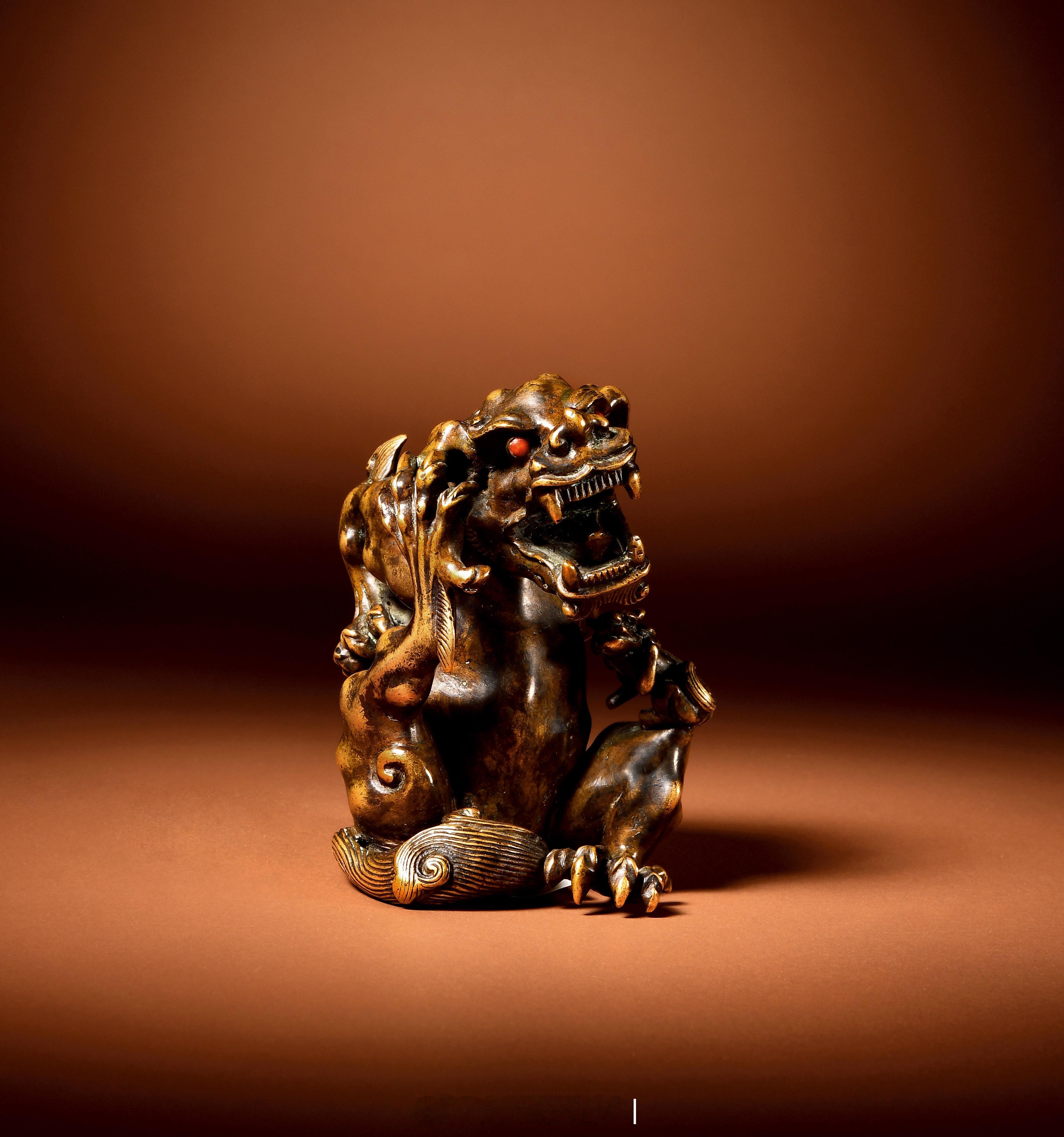 明 铜狮纸镇器作双狮形，以精铜为材熔铸錾刻而成。整体由一大一小两只狮子组成。其中