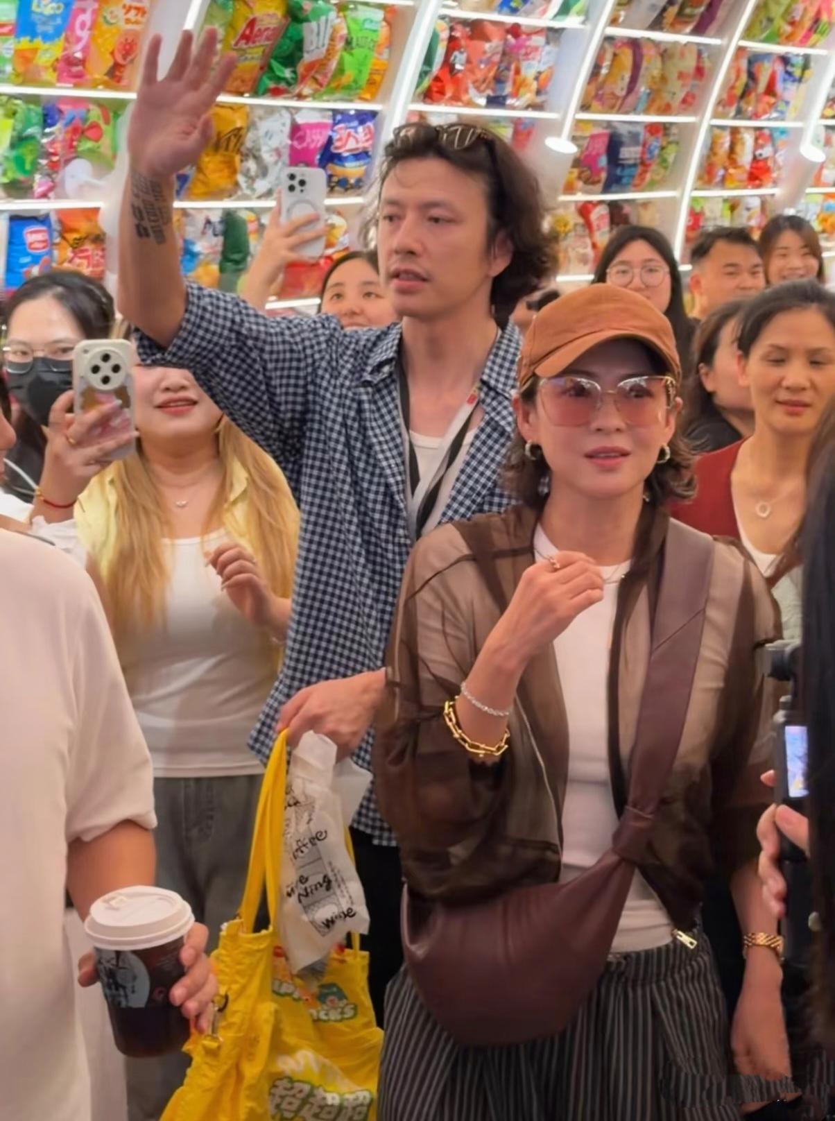 章子怡现身湖南一家零食店，身后一高大蓝色格子衫男子紧紧跟随左右。
     章子