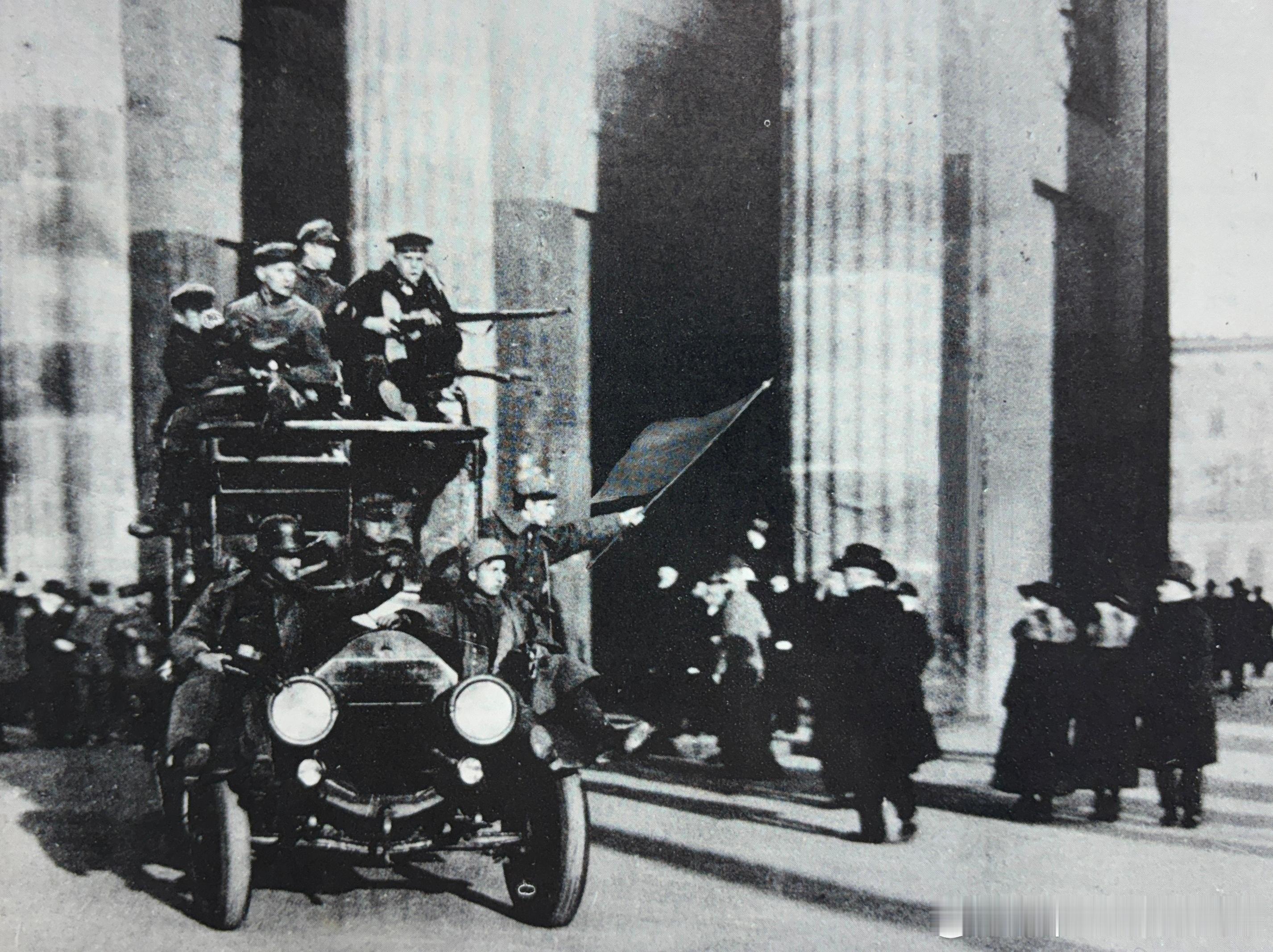 1918年11月9日从前线归来的德军士兵们一边通过勃兰登堡门，一边挥舞着红旗军事