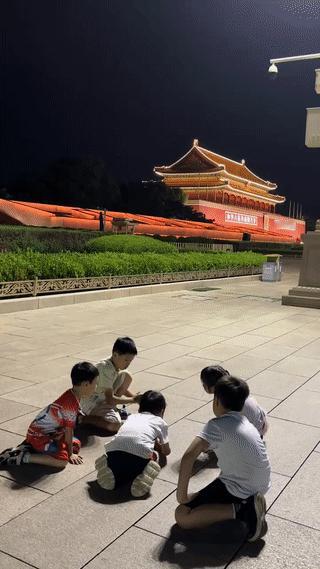 北京天安门广场上拍到的温馨一幕。
有几个小朋友正在广场的一侧地上玩耍。
而在他们