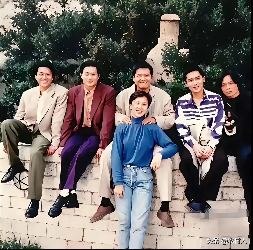 1992年《辣手神探》片场，梁朝伟与周润发并肩而立。身后是忙碌的拍摄场景，两人眉