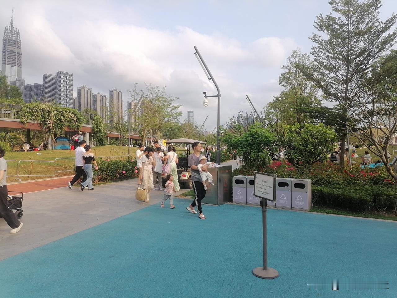 游览车旁俊男靓女在搞什么呢？连廊里草场上休息的游客，小路上快步走的人和年轻爸妈带
