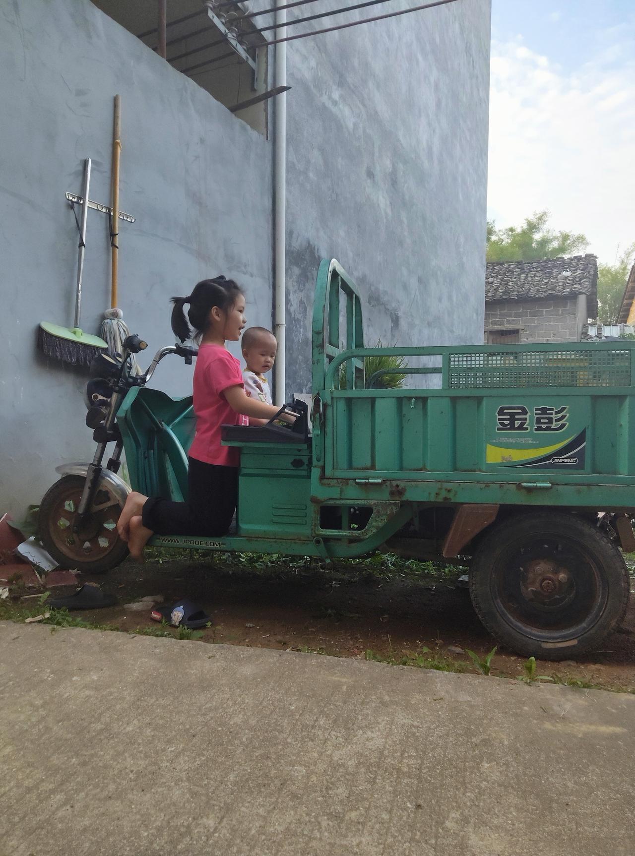 看这画面，瞬间就想起小时候在乡下的日子！姐姐带着弟弟，把家里的三轮车当成“大玩具