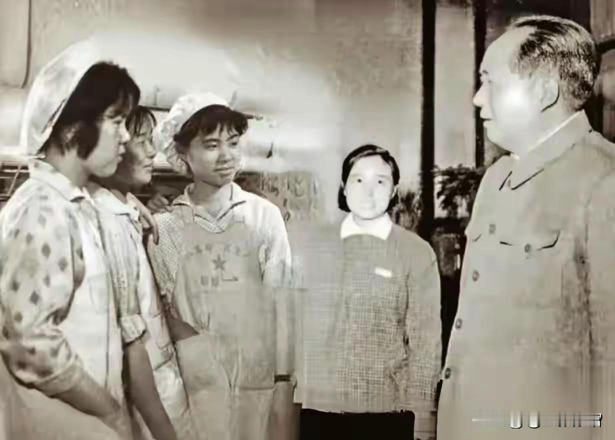 这是一张极具历史意义的黑白照片，记录了毛泽东同志视察纺织企业、与一线纺织女工亲切