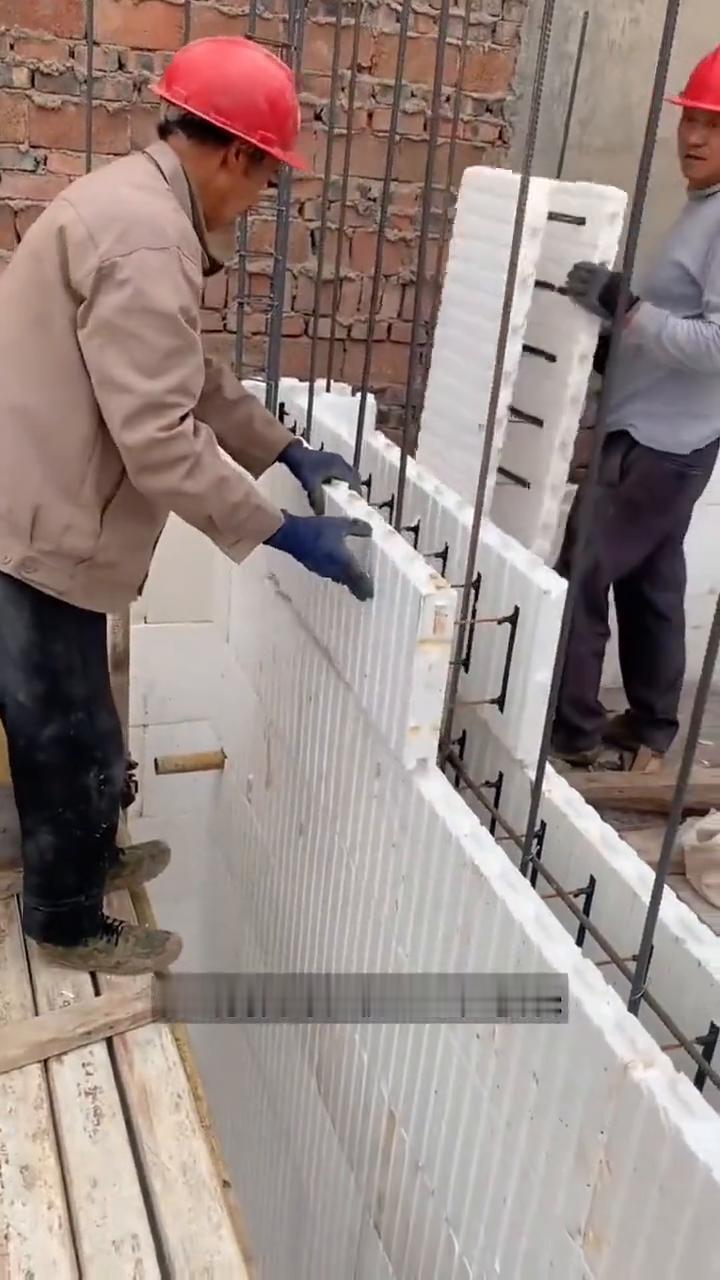 泡沫块建房。
大家注意看，工人正将泡沫模块穿过钢筋，像搭积木似的一块块拼起来。好