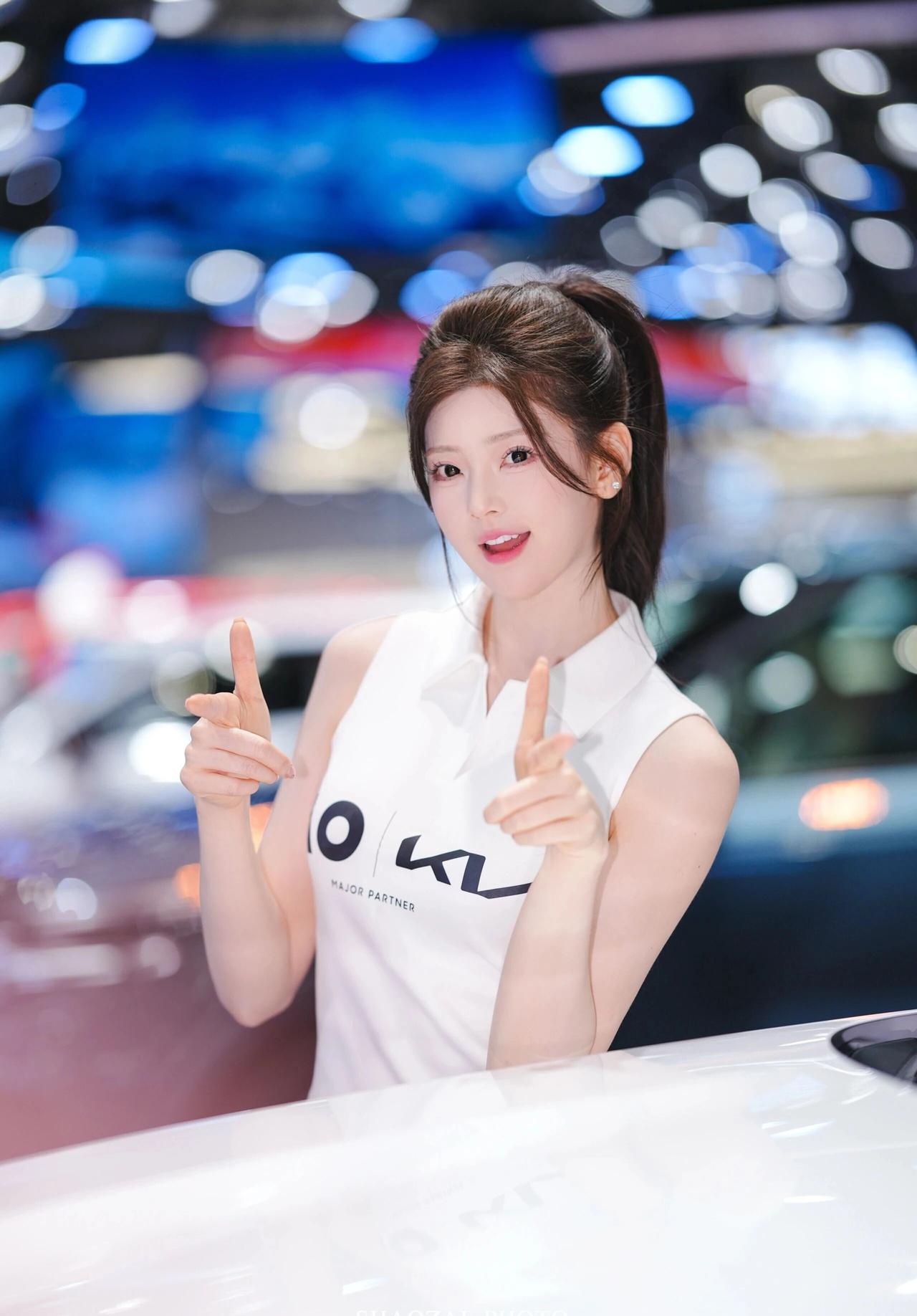 高马尾利落清爽，搭配简约无袖白上衣与绿色百褶短裙，青春感拉满。肌肤白皙透亮，五官