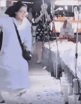 这位身着连衣裙、背着精致小包的女士，在一家专卖瓷器的店里相中了一件瓷器，随即掏出