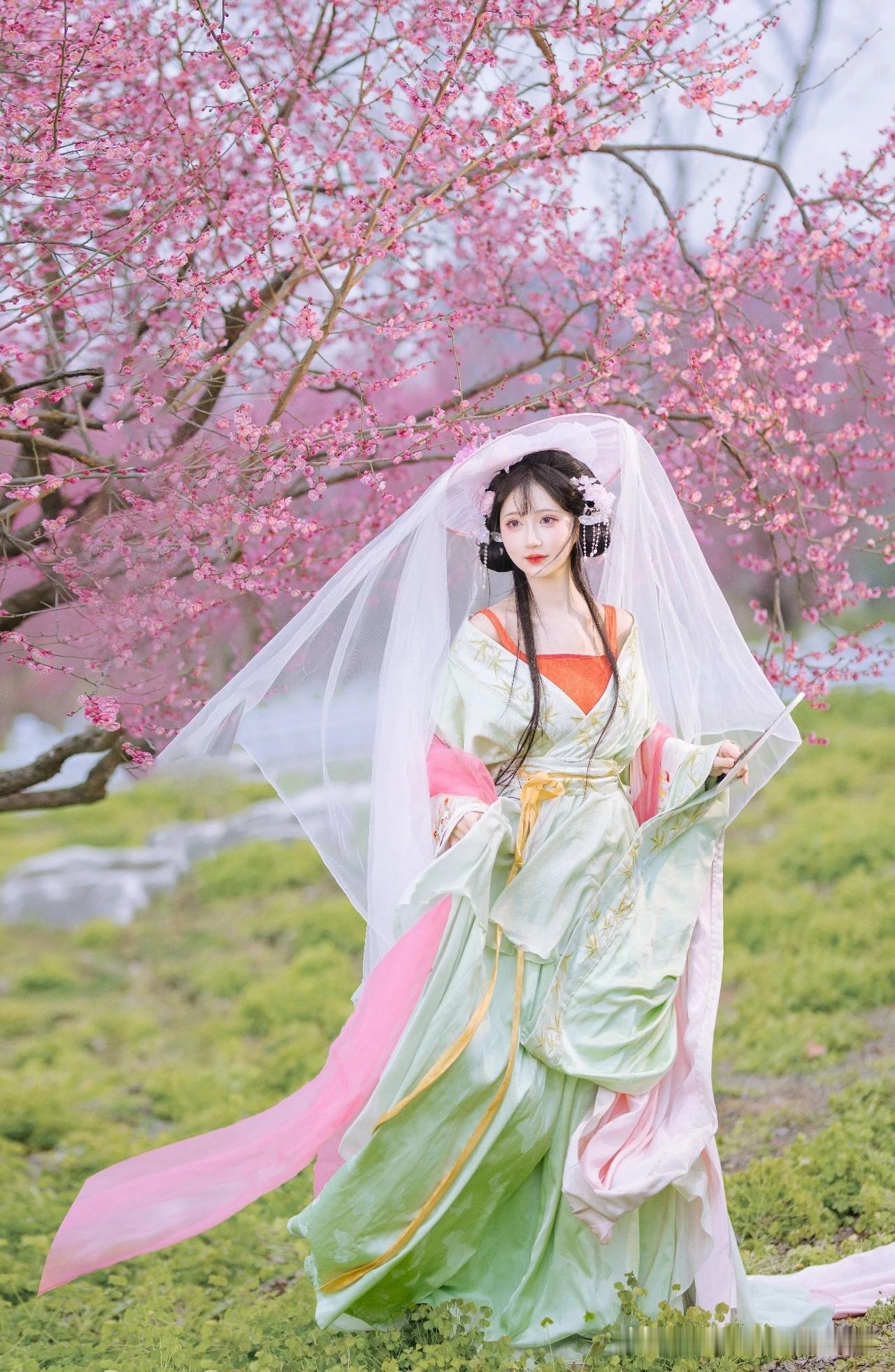 像是从山水画里走出的仙子。
身畔是碧波荡漾的江水，
身后是连绵起伏的青山。
不需
