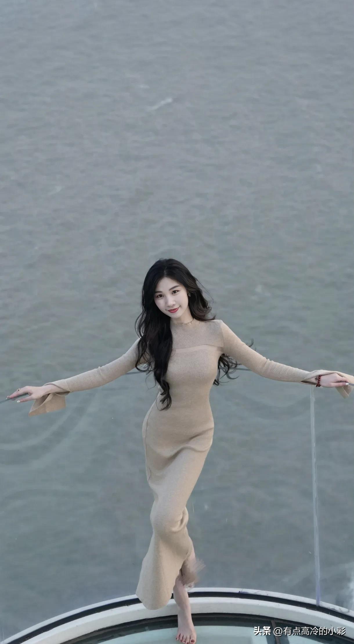 浅米色针织裙勾勒出温婉轮廓，长发微卷随风轻舞，手抚发丝的瞬间，尽显优雅从容。腕间