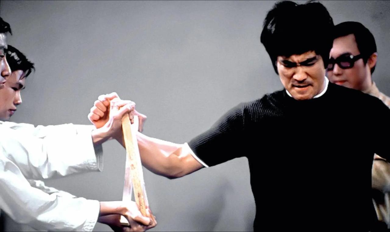 李小龙在综艺节目《欢乐今宵》中的现场表演画面。
李小龙让助手拿着木板，然后，李小
