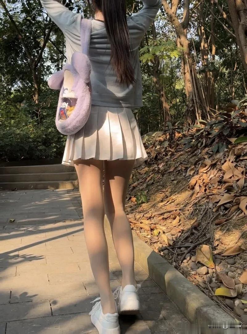 温柔感直接拉满！这套浅灰开衫+百褶裙的穿搭，谁穿谁好看！
女生站在 公园长椅 旁