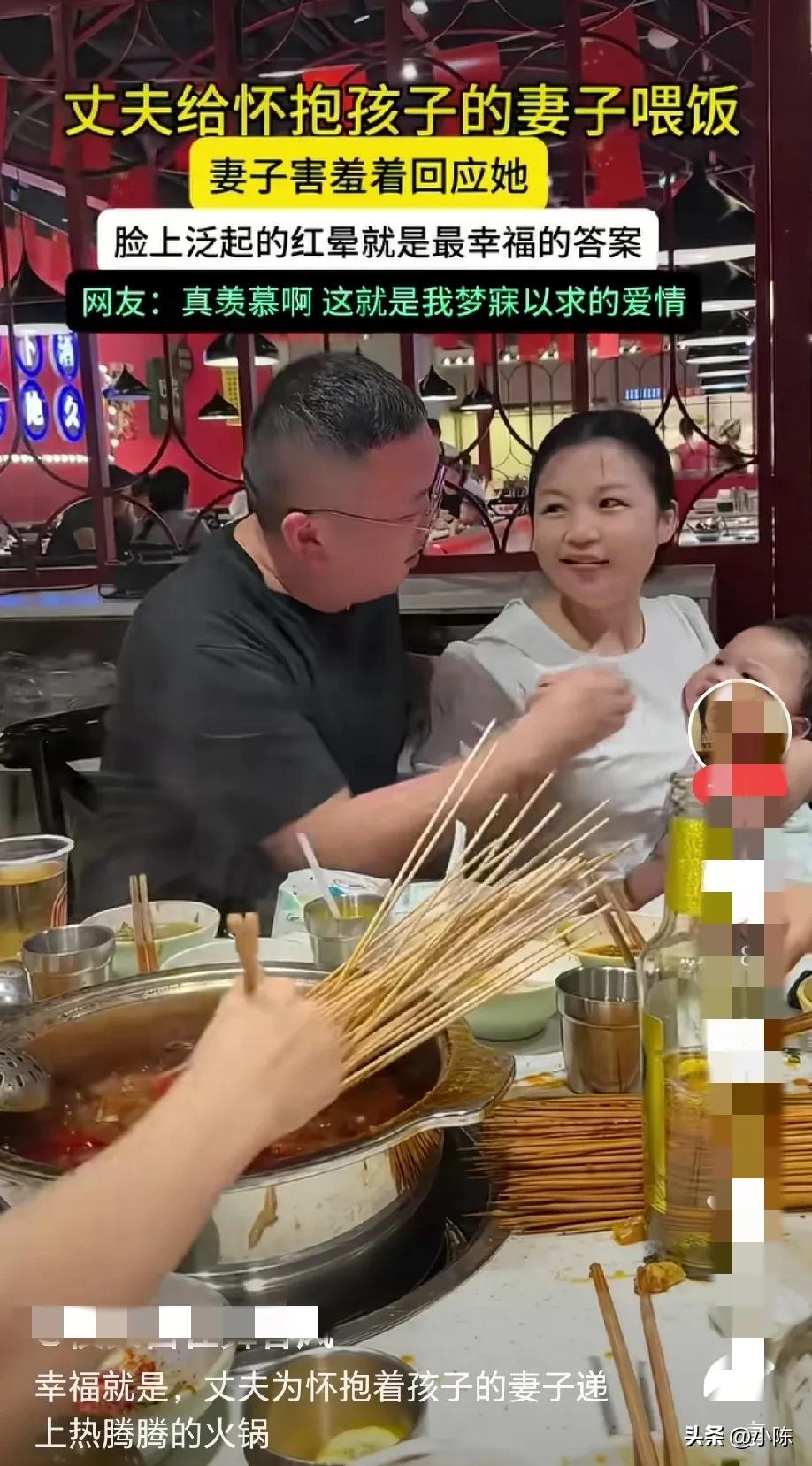 这就是幸福！丈夫给怀抱孩子的妻子喂饭，妻子一脸害羞着回应他，脸上泛起的红晕就是最