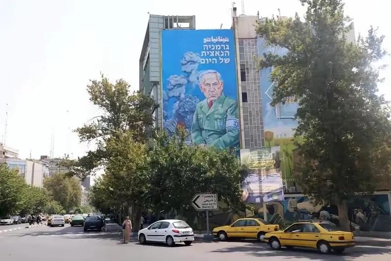 以色列总理内塔尼亚胡的巨型画像被伫立在德黑兰繁华街头，画里面是以火光四溅、黑烟弥