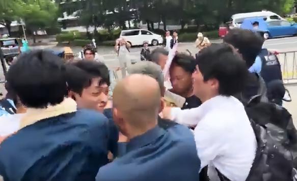 活该！一名精日台湾男子举着"我欢迎日本再次侵华"的牌子，头上还披着乌克兰国旗，像