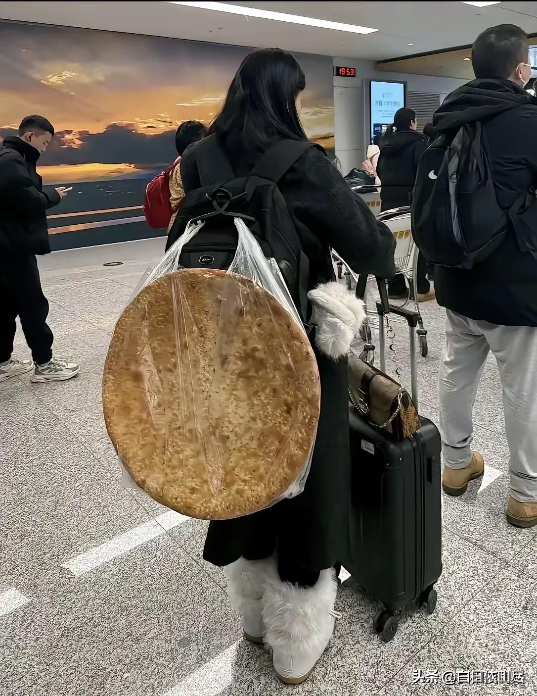 一女子在机场等着过安检，万万没想到女子的背上竟然背了一个硕大无比的馕，远看这馕占