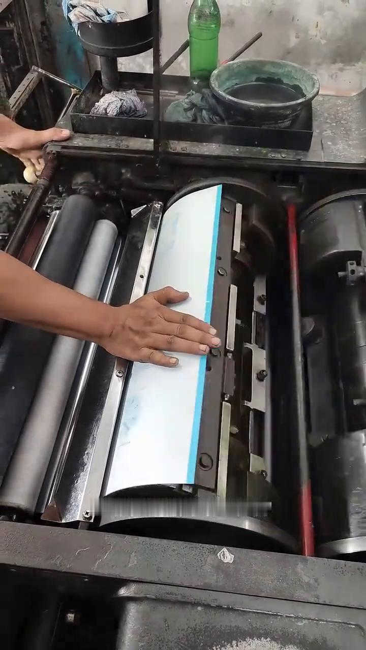 视频展示的是印刷师傅正在给胶印机安装PS版，但这薄薄的金属板是如何将图案印到纸上
