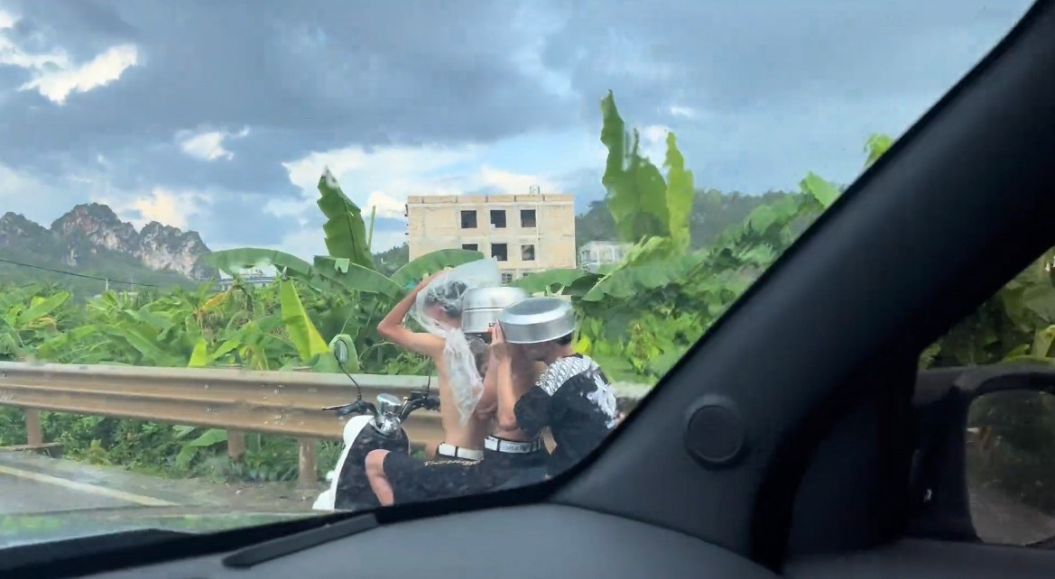 【玉林一电车后坐两名男子拿锅挡雨】近日，玉林市某乡镇道路上一辆电动车坐着3名男子